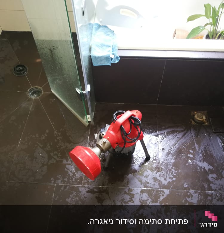 מכונת ניקוי אדומה על רצפת חדר אמבטיה רטובה